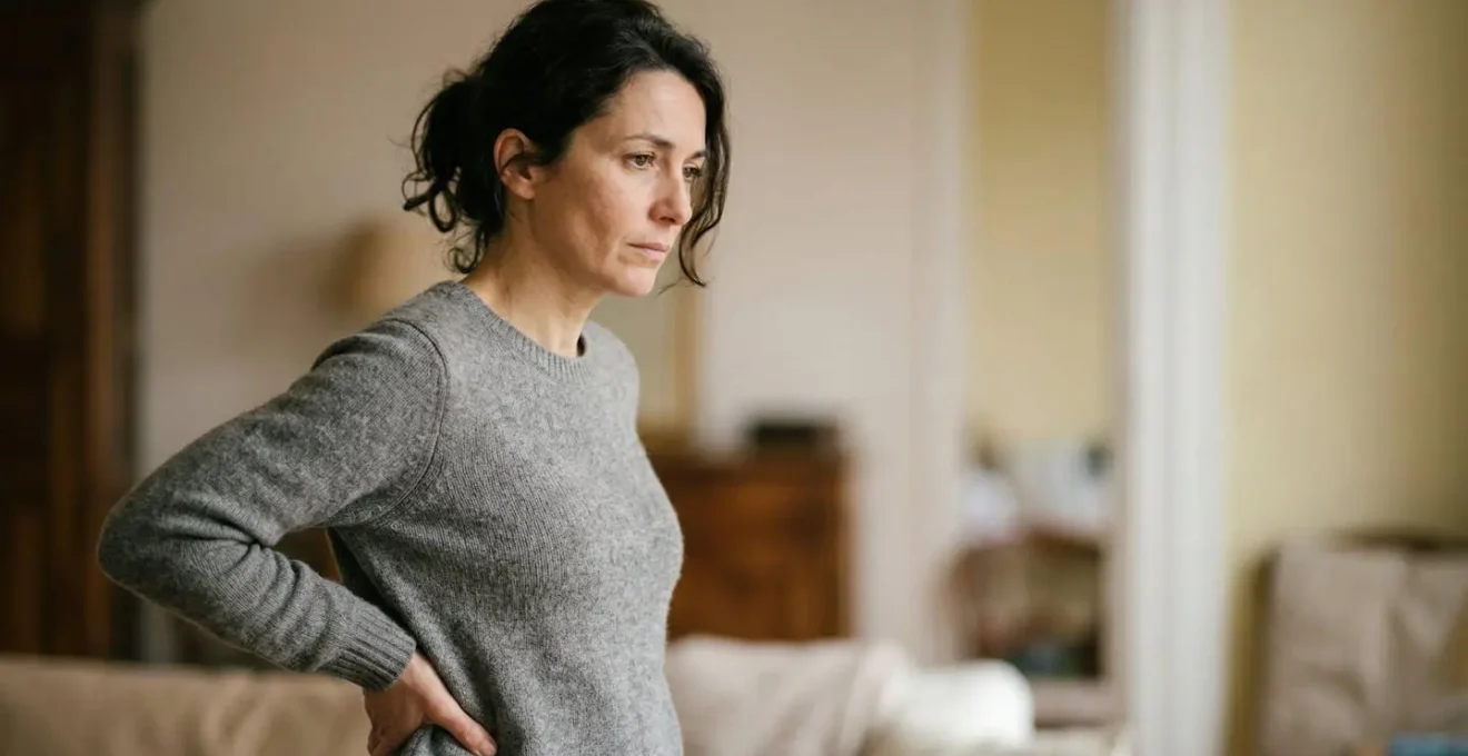 Personne touchant son bas du dos avec expression de douleur et questionnement