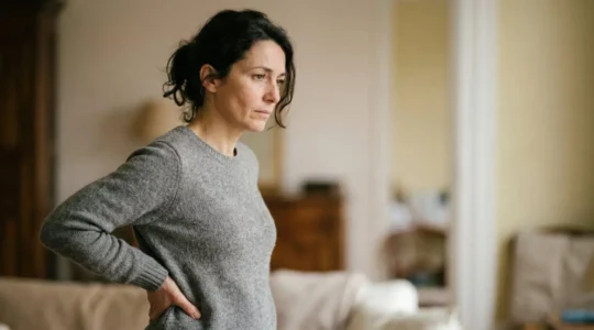 Personne touchant son bas du dos avec expression de douleur et questionnement